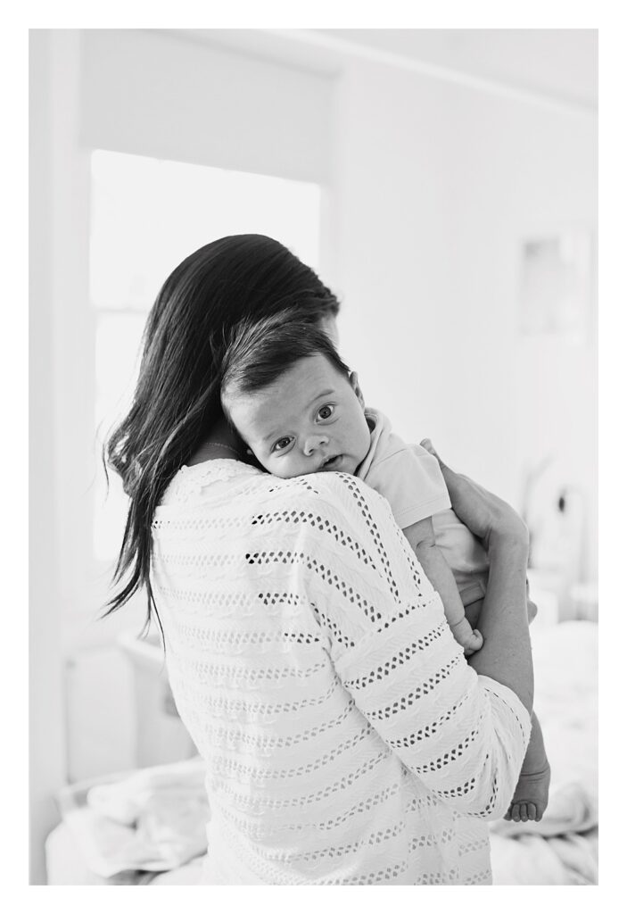 Baby boy rests on mother's shoulder during photo shoot at home in Kensington, London