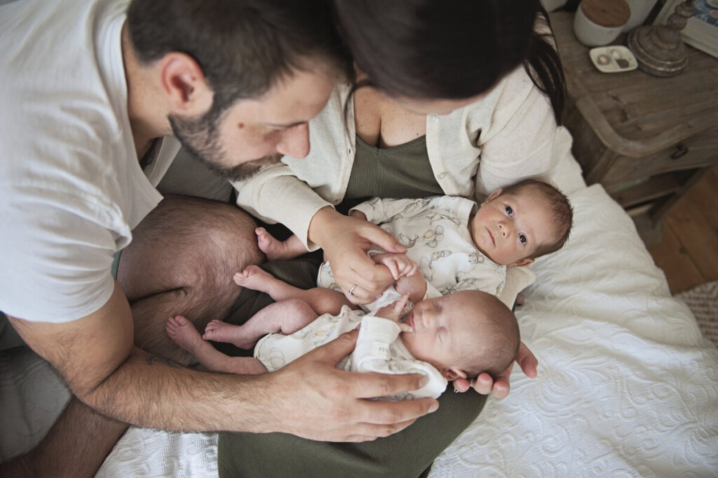 A couple looking lovingly at their newborn twins for a relaxed newborn photoshoot in London