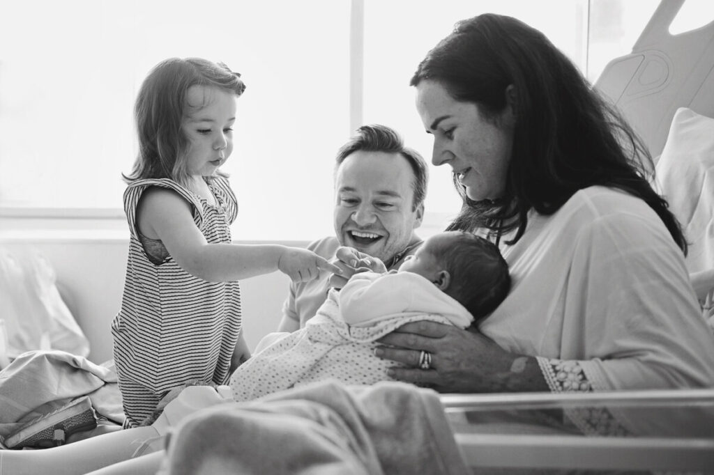 Image of a family in the hospital holding their newborn baby at a Westminster Suite newborn photo shoot, St. Thomas' Hospital in London