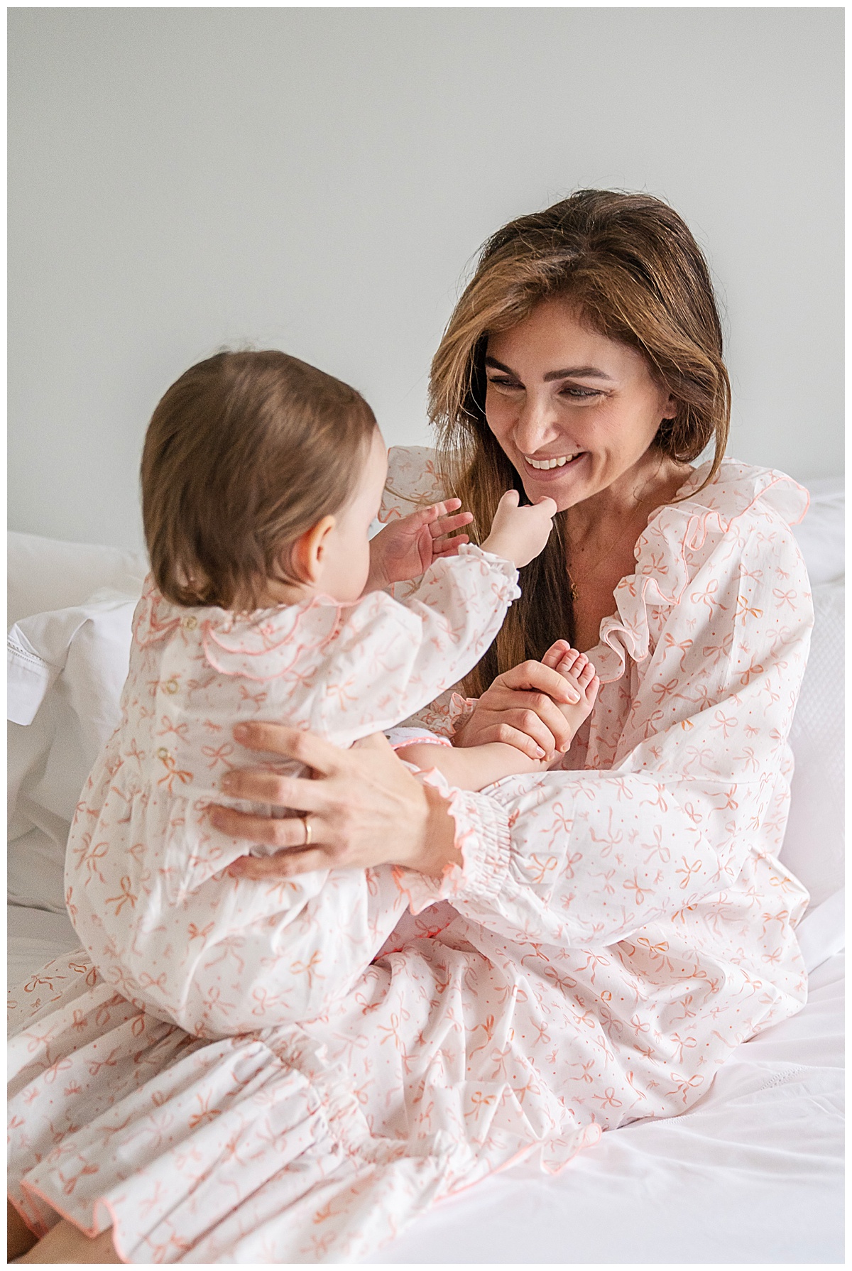 A mother wearing a beautiful printed nightdress plays with her baby daughter who wears a matching romper.
