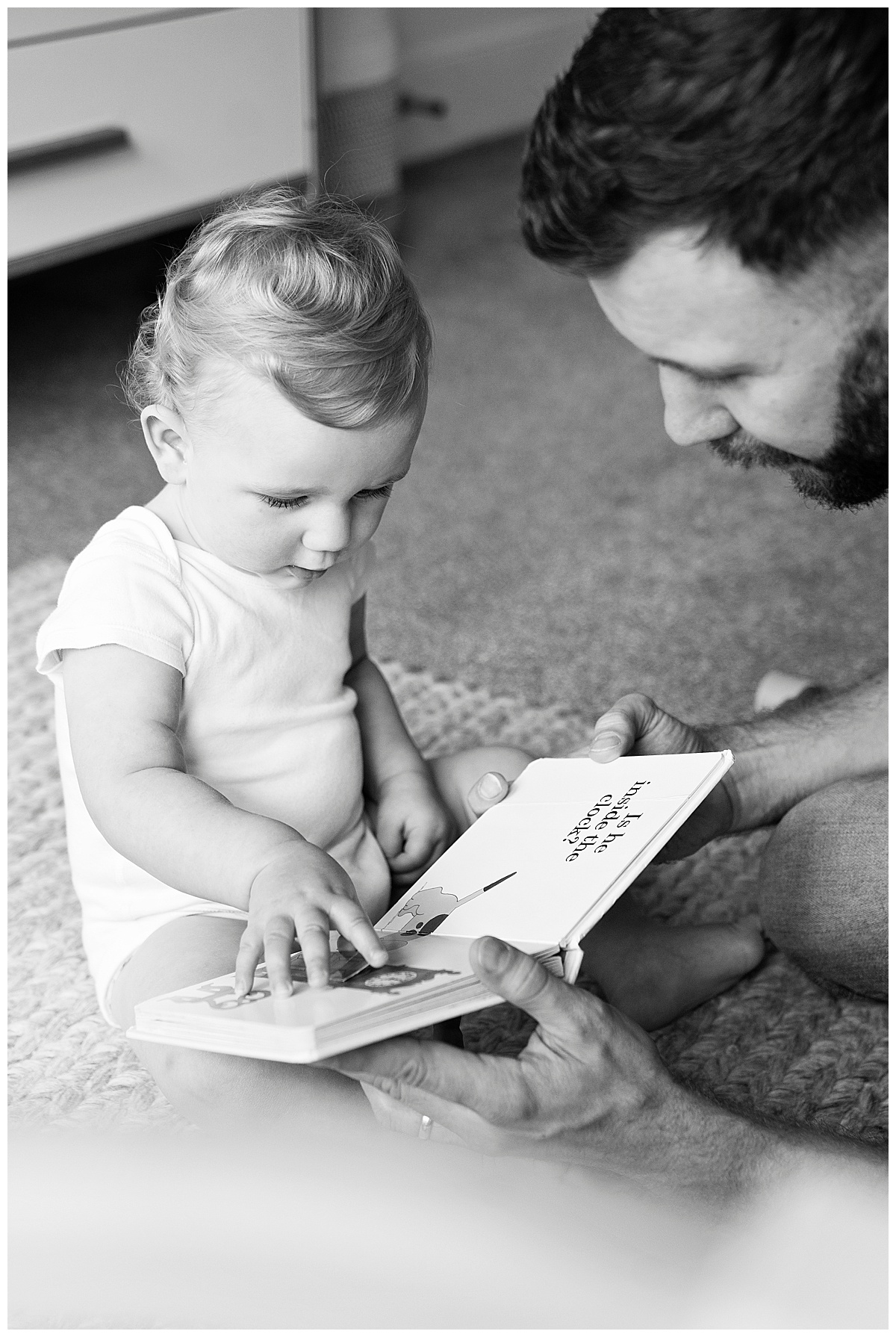 One year old baby looking through his favourite book while he poses for his first birthday photo shoot