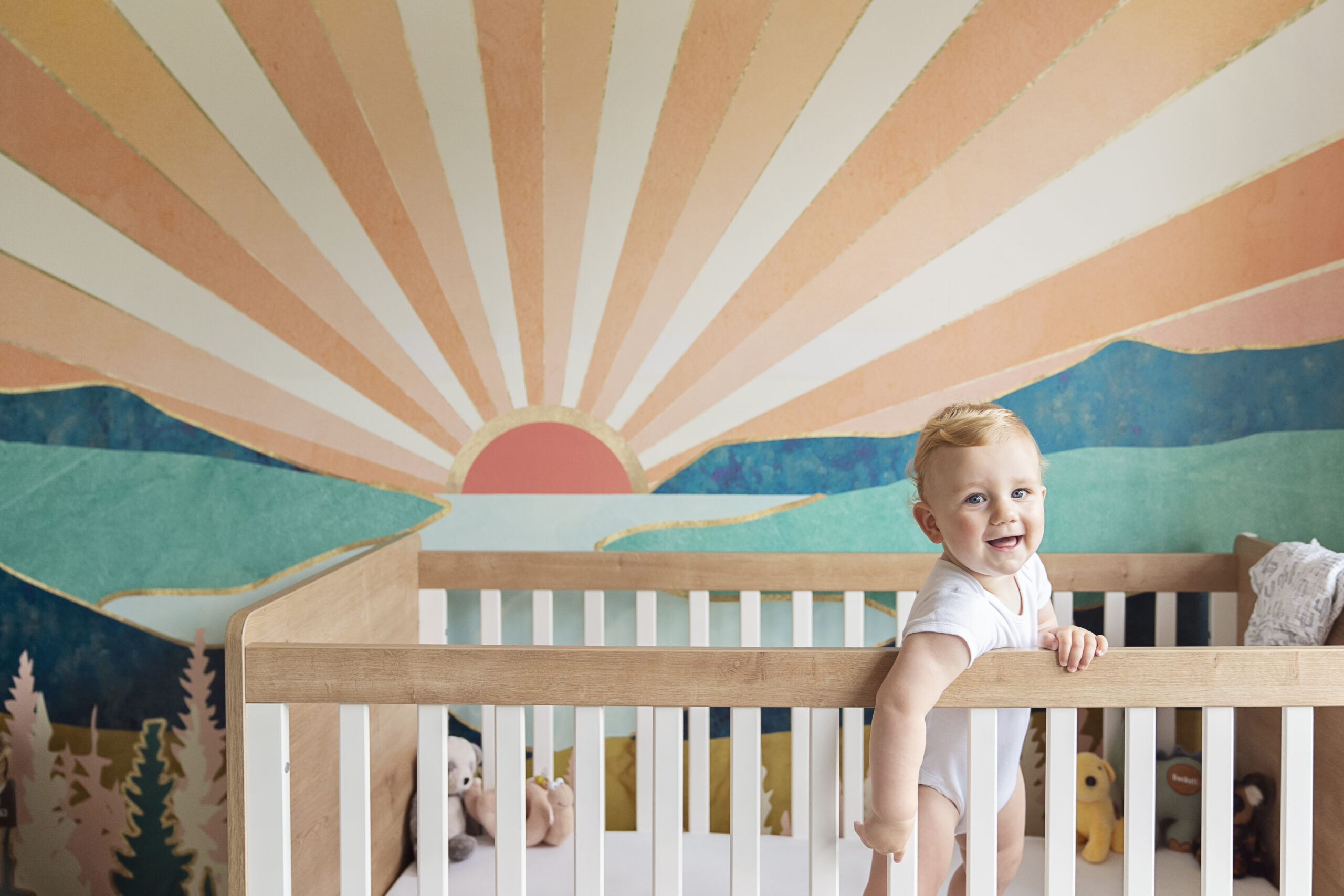 One year old baby boy standing in his cot on his first birthday during a family photo shoot