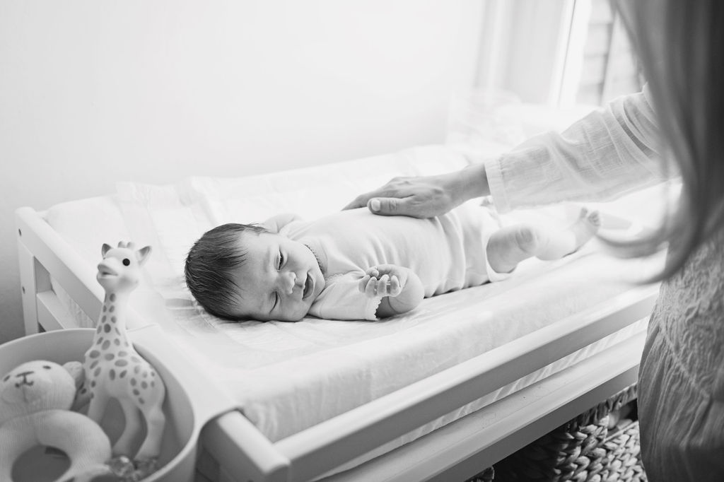 A newborn baby lying on a changing mat having their picture taken for an at home newborn photo session