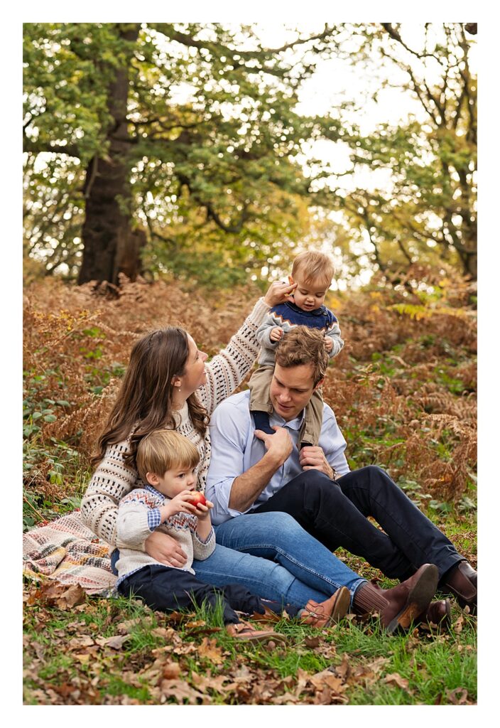 
Family sitting on a blanket posing for an Autumn Family Photoshoot in Richmond Park, London
