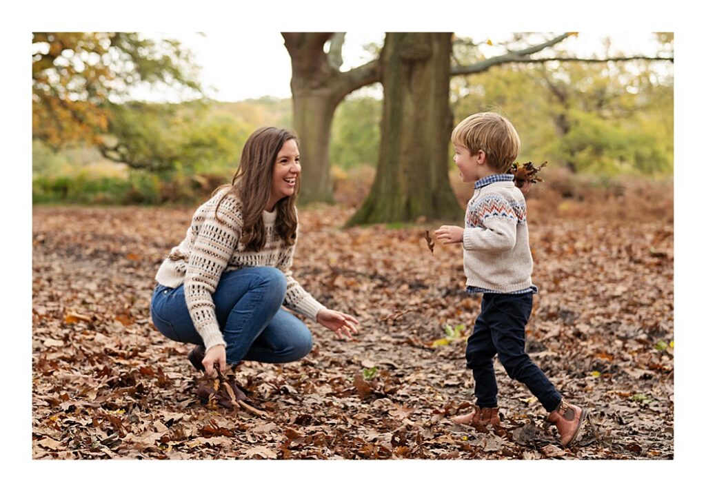 Mum playing with her son in a pile of leaves for an Autumn Family Photoshoot in Richmond Park in London