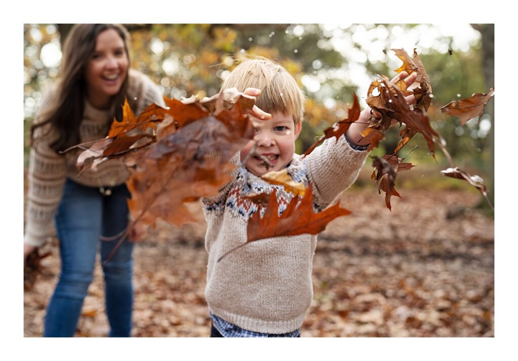 A small child playing with autumn leaves