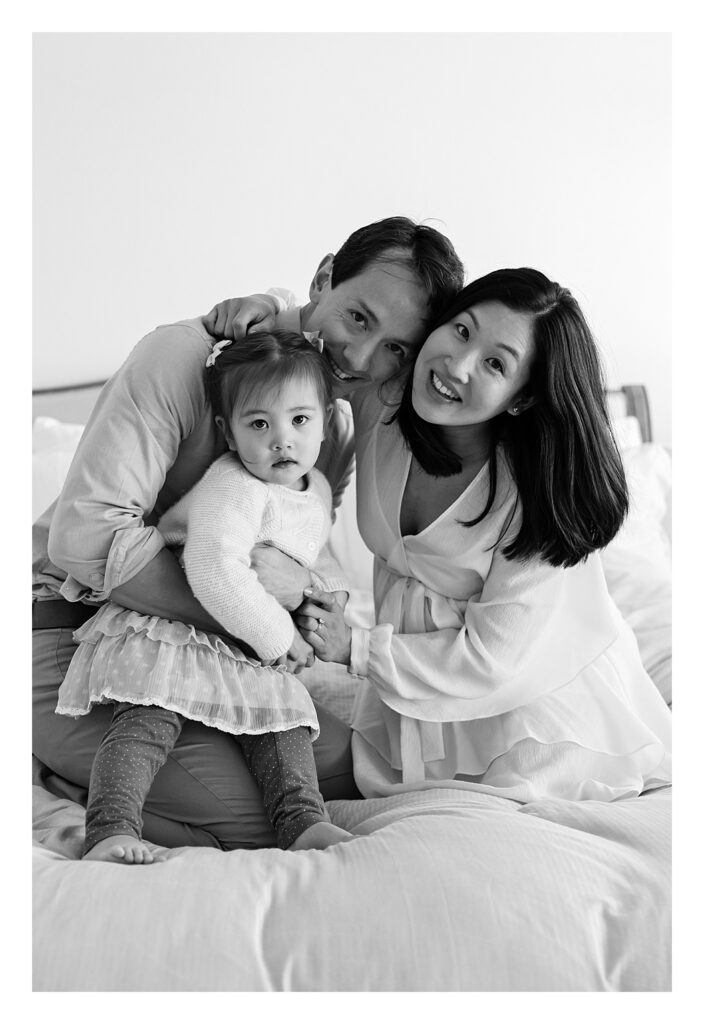 Family group hug on bed during a family photo shoot celebrating being pregnant with their second baby.