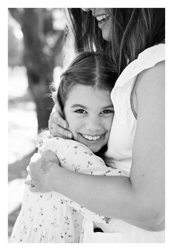 A mother and daughter hug during a summer photo session in Bushy Park