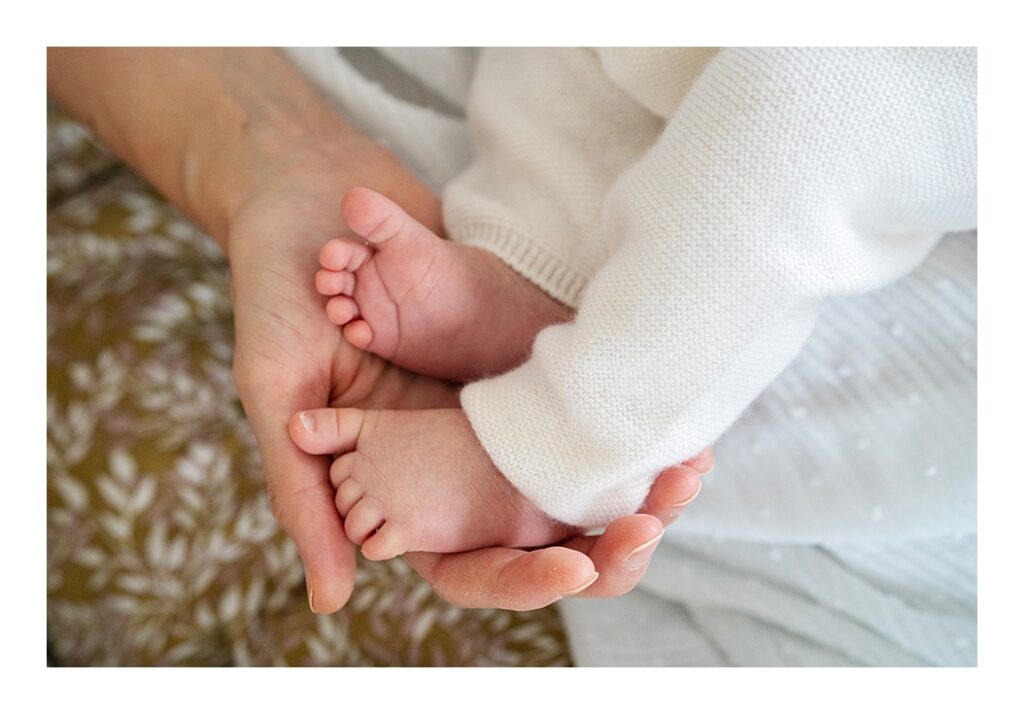Newborn baby feet held in mother's hand