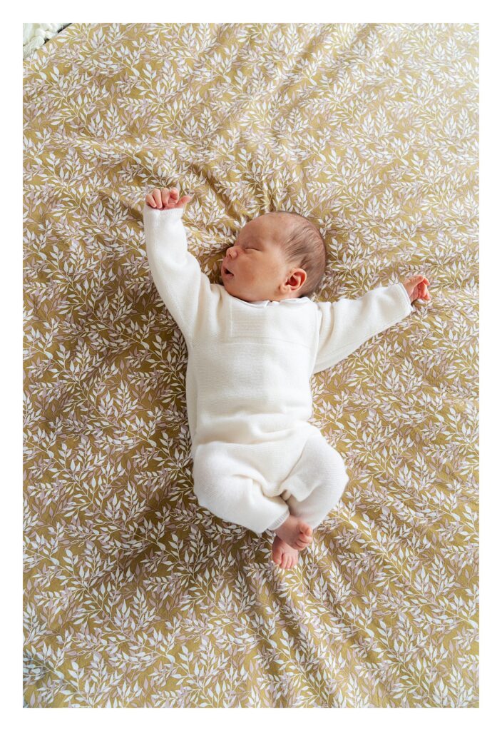 newborn baby boy stretches on bed
