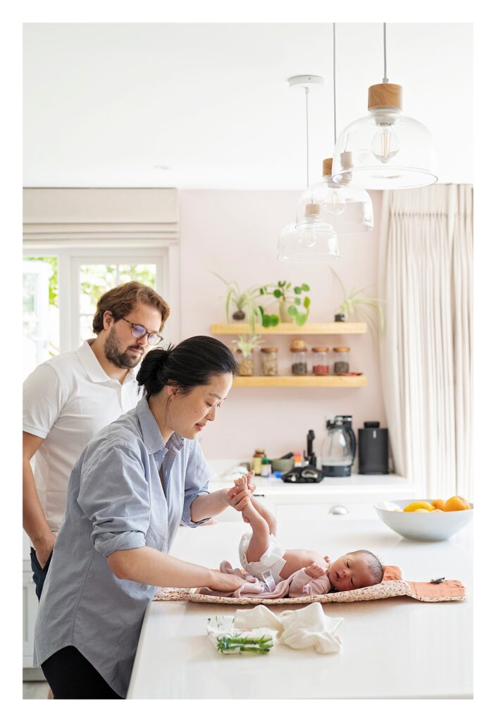 A newborn baby has her nappy changed on the kitchen counter during a documentary newborn photo shoot at home in Weybridge, Surrey

