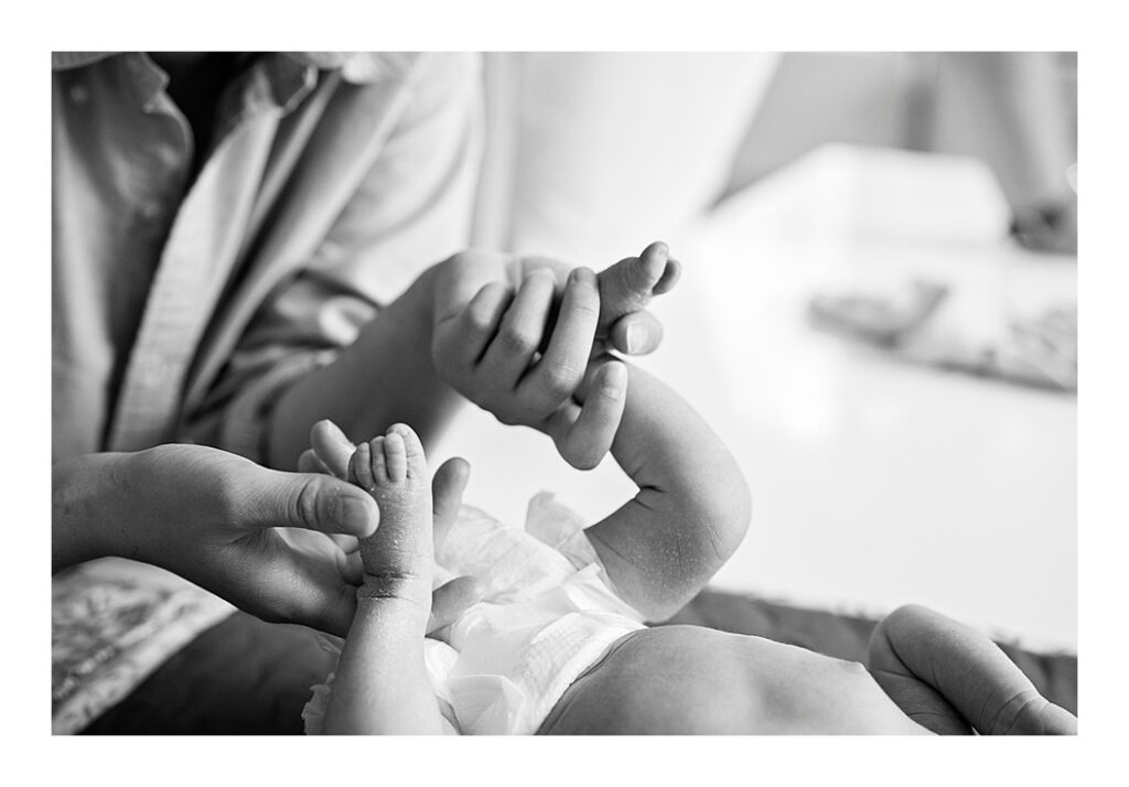 Mother plays with her newborn baby's feet during a nappy change
